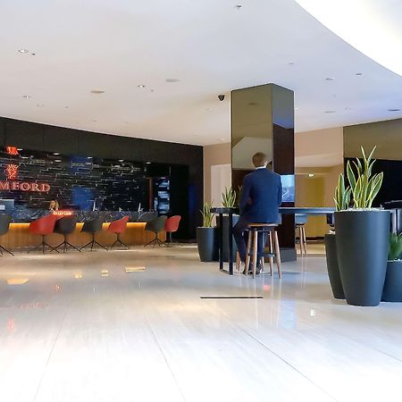 Stamford Plaza Sydney Airport Hotel & Conference Centre Exterior photo The photo shows the interior of a modern hotel lobby. In the background, there is a stylish reception area with the word "STAMFORD" prominently displayed. The seating consists of colorful chairs around tables, and the design features a sleek, contemp
