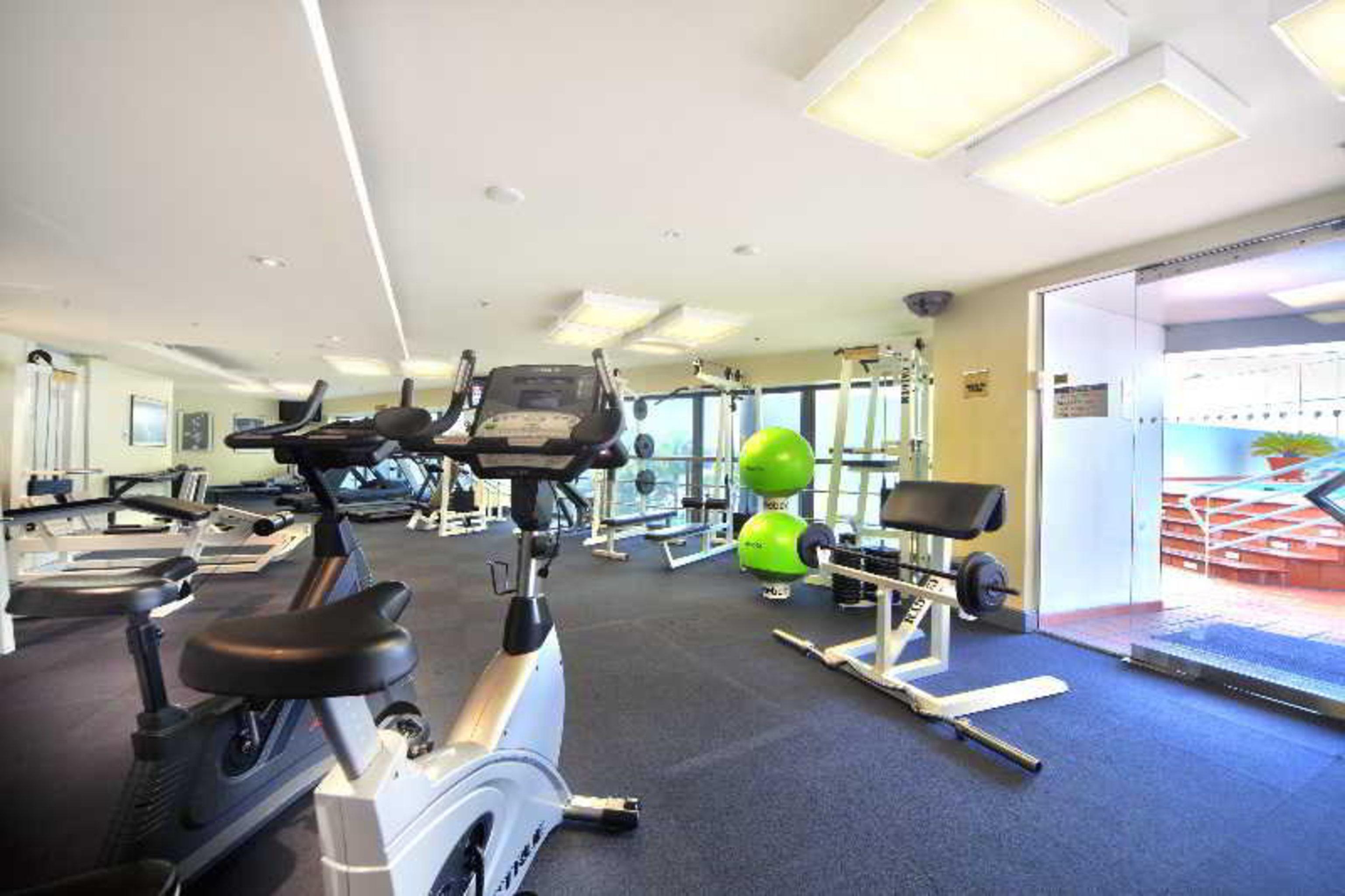 Stamford Plaza Sydney Airport Hotel & Conference Centre Facilities photo The photo shows an indoor gym or fitness area. It features several exercise machines, including stationary bikes and strength training equipment. There's also a bright green exercise ball and mirrors on the walls, which help create an open and spacio